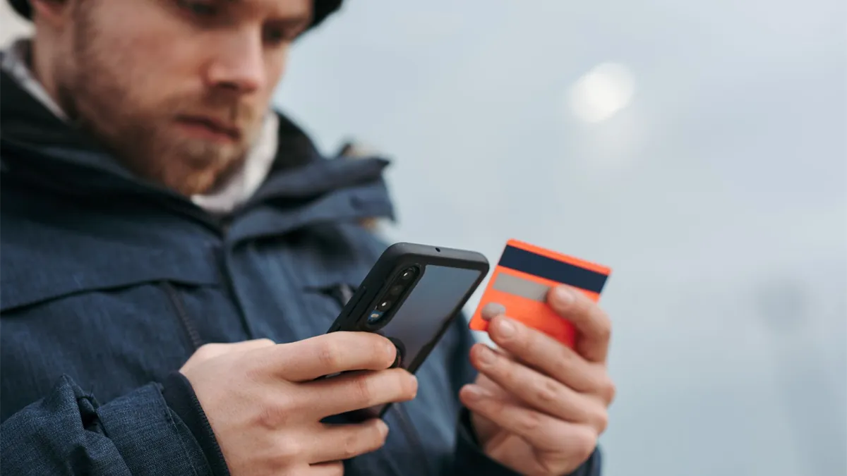 Man paying with a secured credit card and phone to build credit