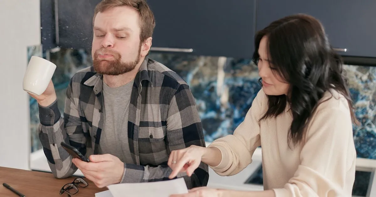 Debt settlement in Canada: couple reviewing overdue bills at their kitchen table