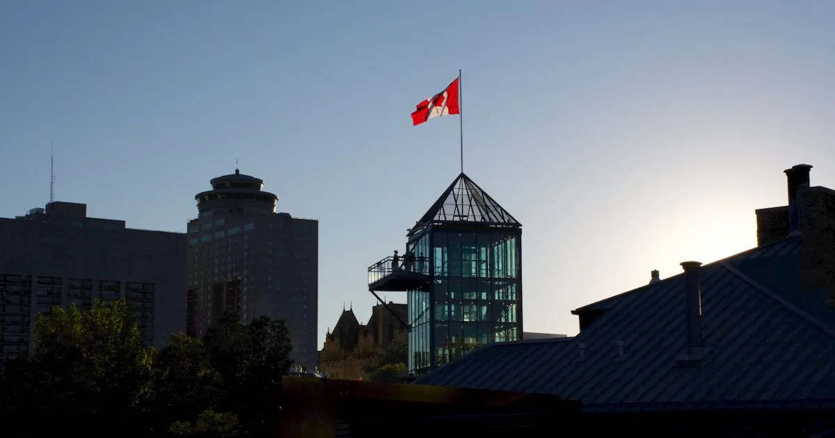 Debt consolidation Winnipeg: downtown skyline silhouette with Canadian flag at dusk