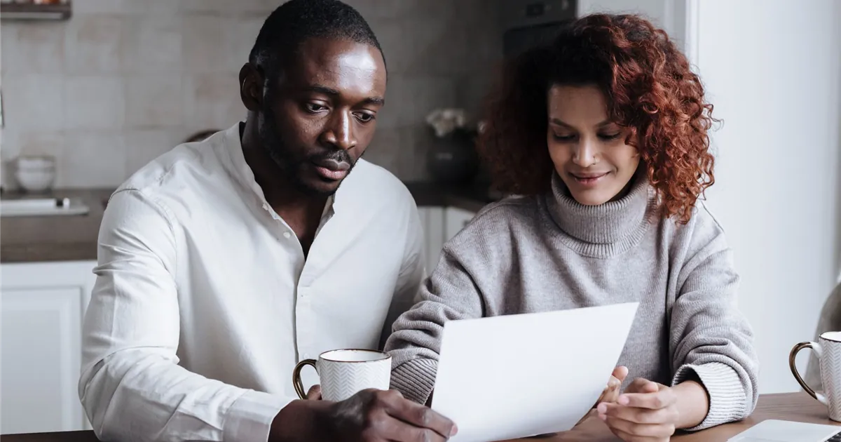 Couple at their kitchen table reading a letter about their consumer proposal