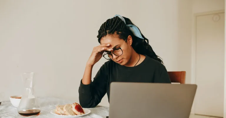 Woman at her kitchen table reading her credit report on a laptop before starting credit repair