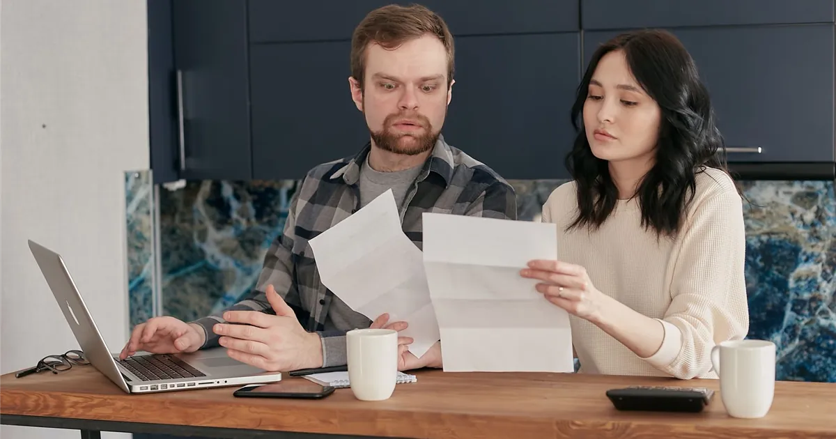 Couple at their kitchen table reading the terms of a joint consumer proposal