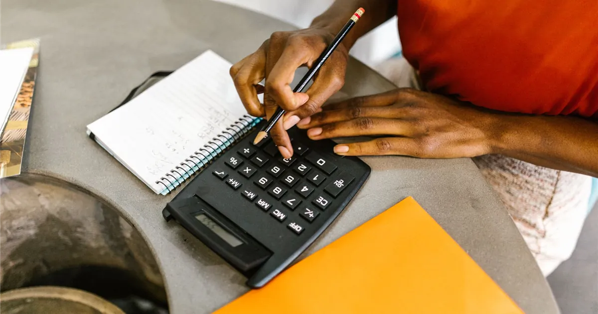 Woman working out a monthly budget with a calculator to rebuild credit after a consumer proposal