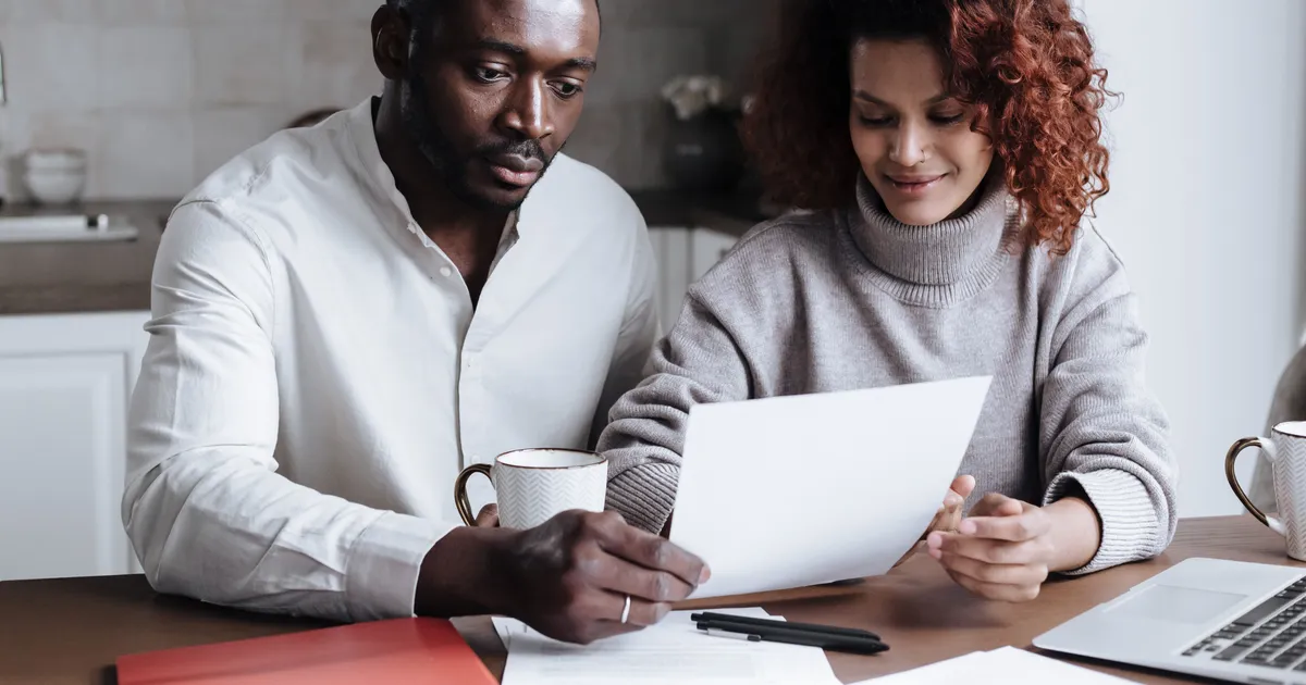 Couple at their kitchen table reading their credit report together before starting credit repair in Canada