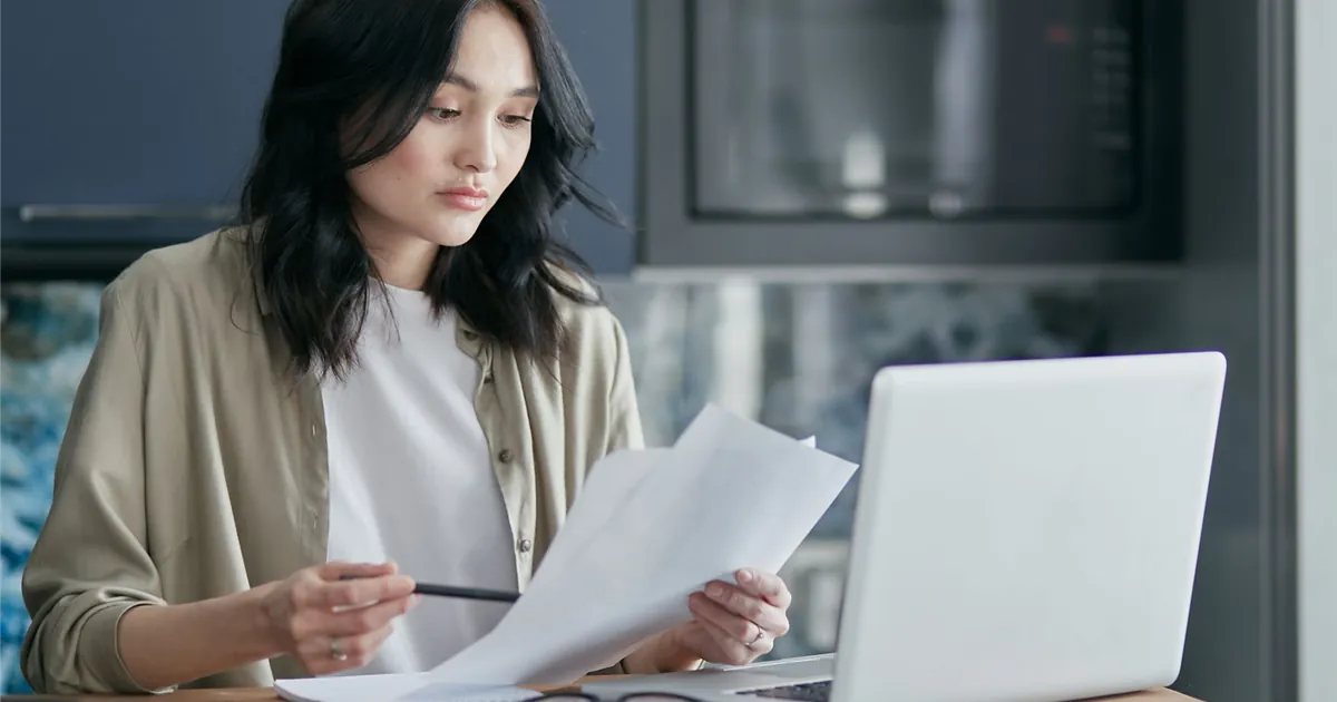 Woman comparing her credit report against bank statements to remove late payments reported in error